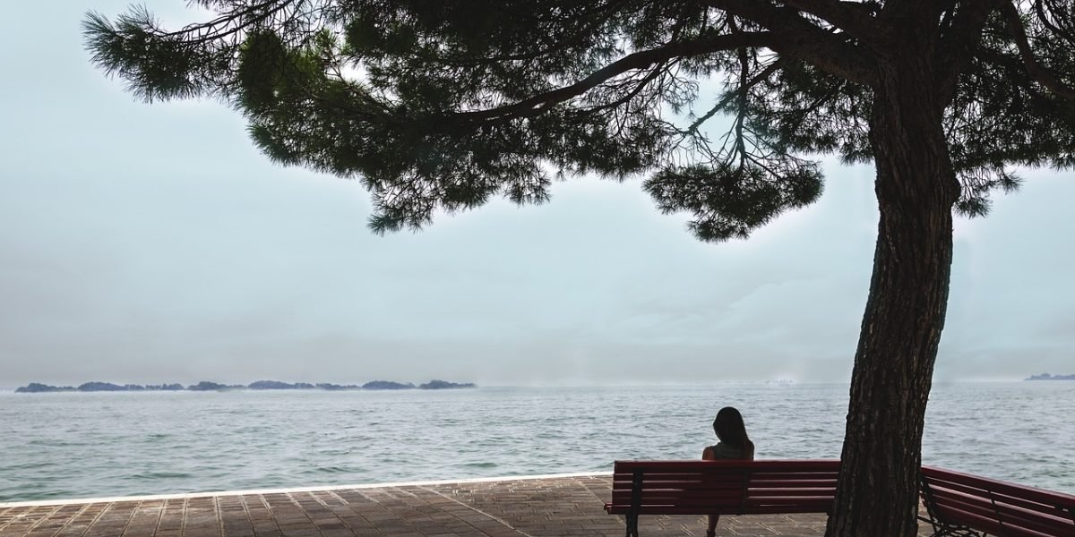 A person contemplating a difficult decision, representing the internal struggle to overcome barriers to self-care.