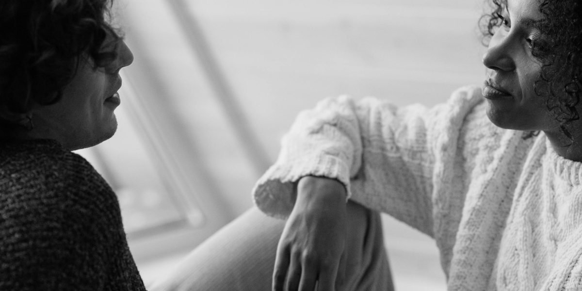Two people engaged in a supportive and empathetic conversation, representing the core of humanistic therapy.