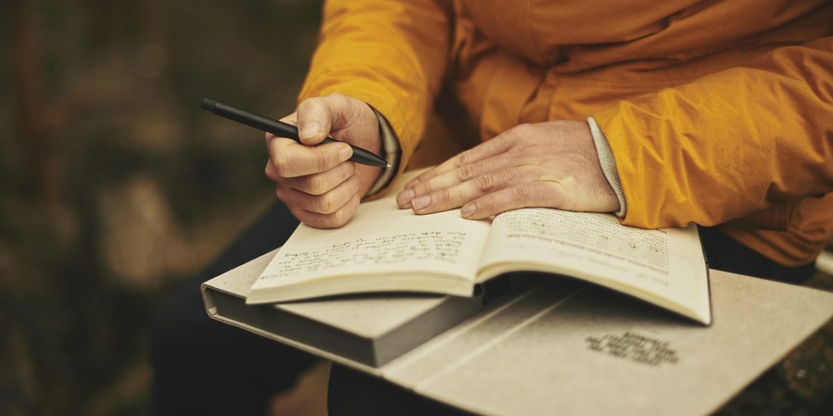 An individual thoughtfully writing down personal goals, emphasizing self-reflection and independent progress.
